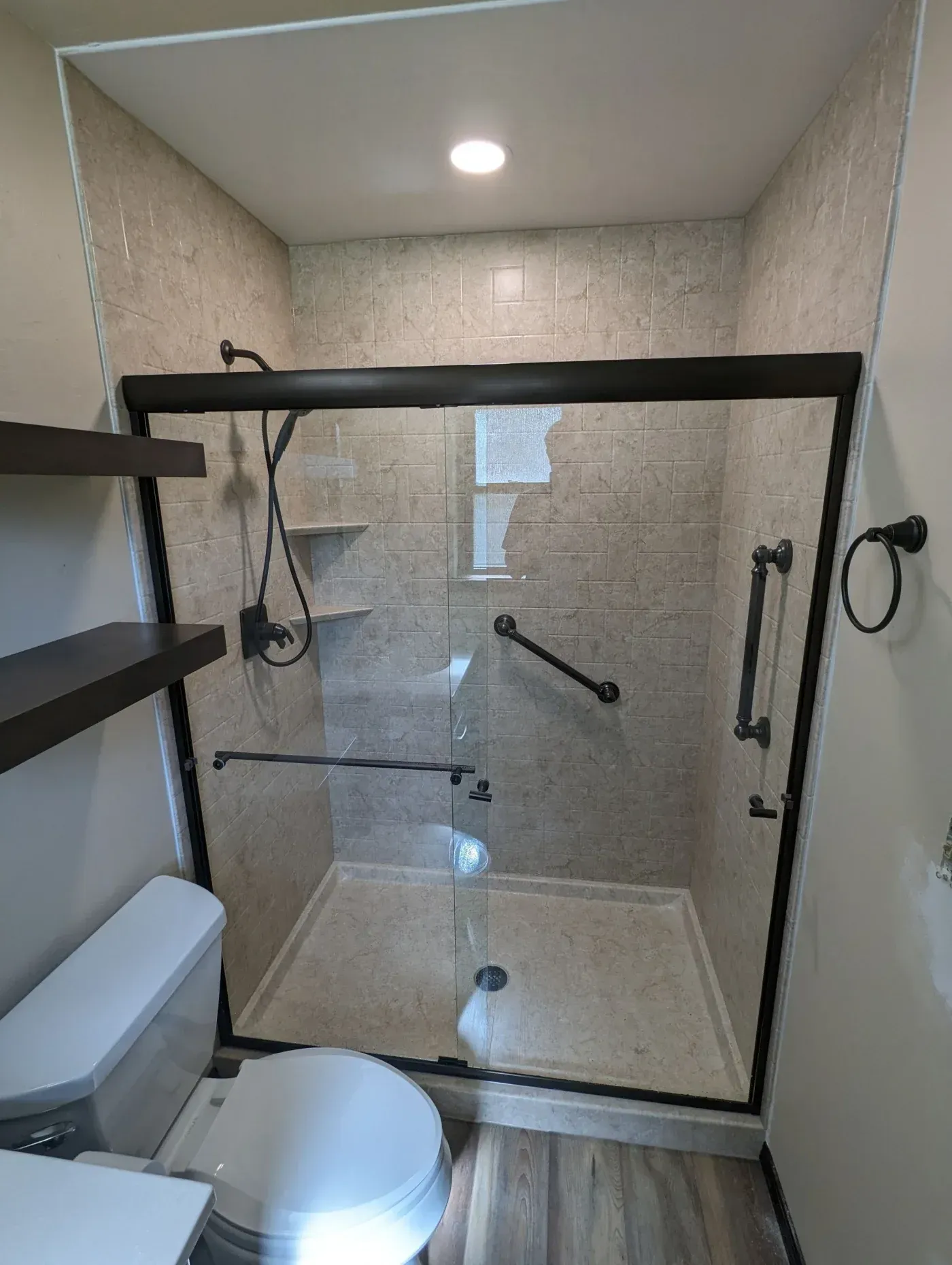 Walk-in shower with breccia-style walls and oil-rubbed bronze fixtures in the Morgan bathroom remodel.