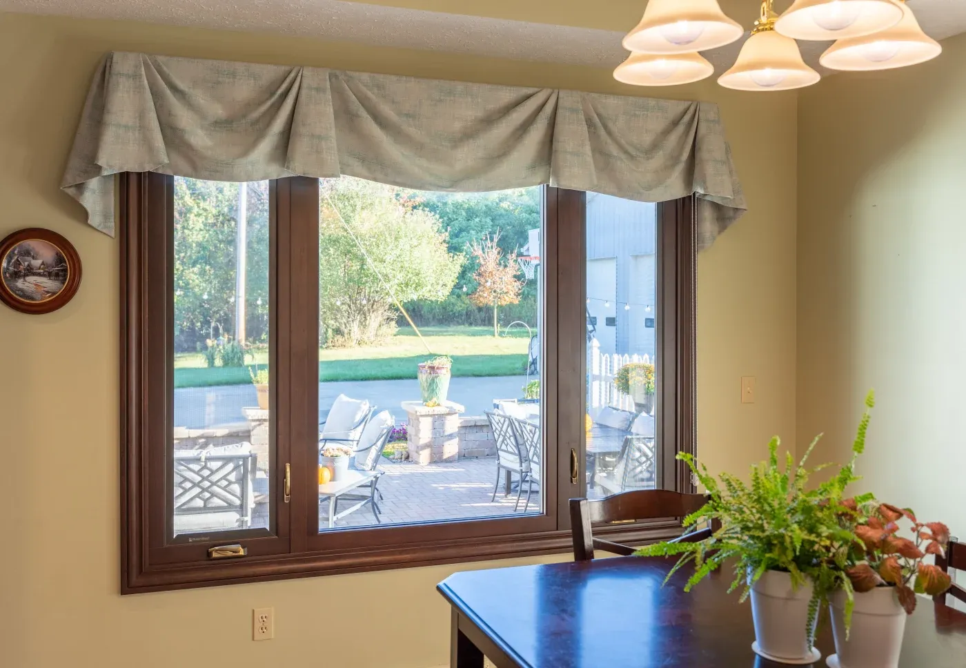 The inside of an NW Arkansas home’s dining room, showing a large picture window with casement with wood clad and a hazelnut stain.