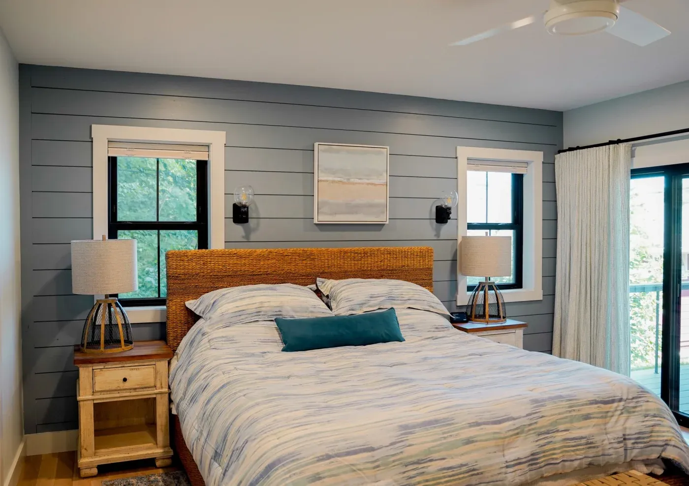 A bedroom in an NW Arkansas home with a large bed and end tables and new double-hung windows on either side in textured matte coal black.