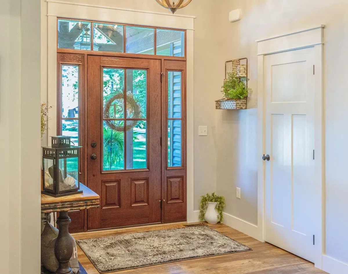 The inside of an entryway to an NW Arkansas home with new front doors with four sections of glass and side lites with mahogany trim.