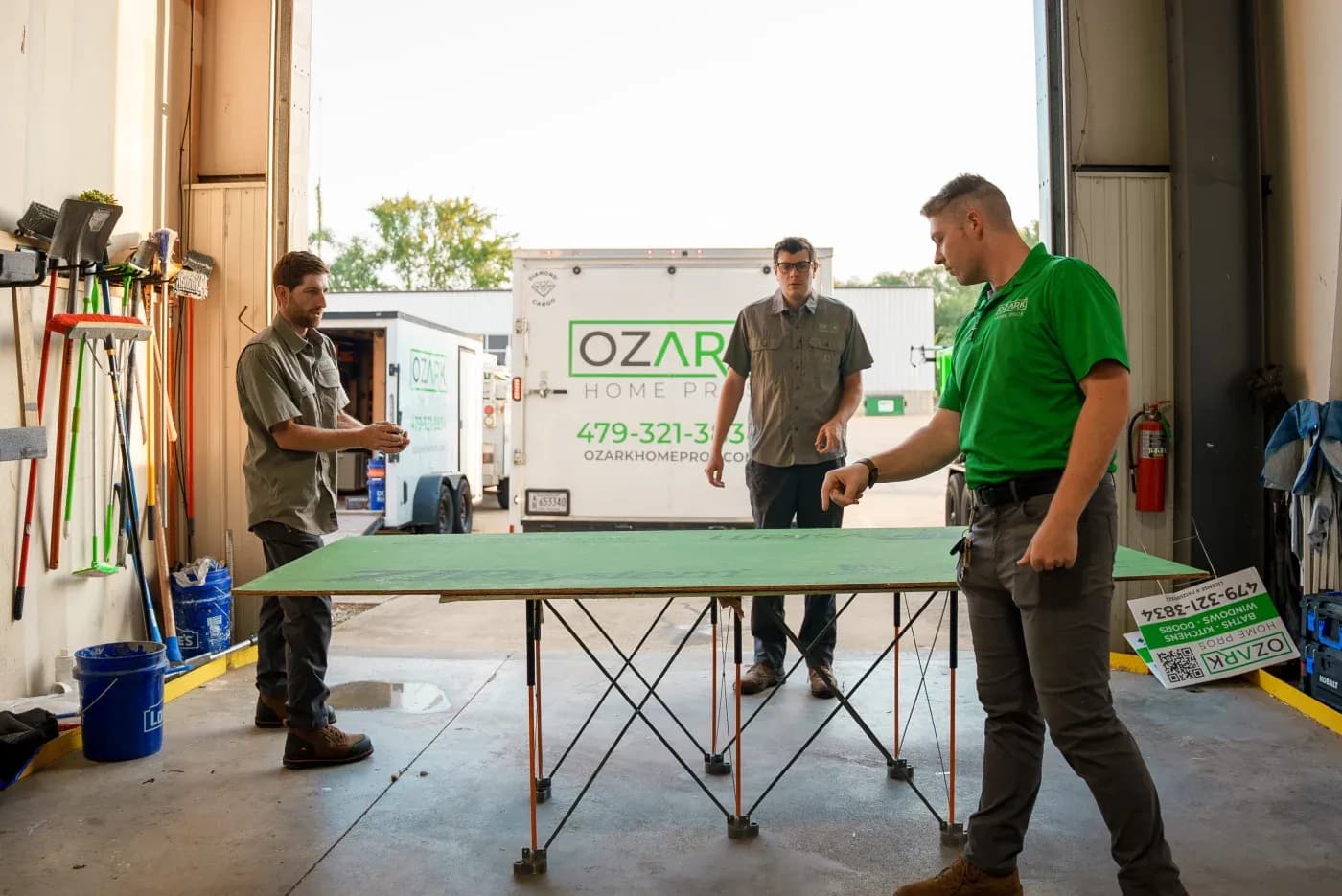 Three of the Ozark Home Pros crew in their warehouse getting ready to head out on a job in Northwest Arkansas.