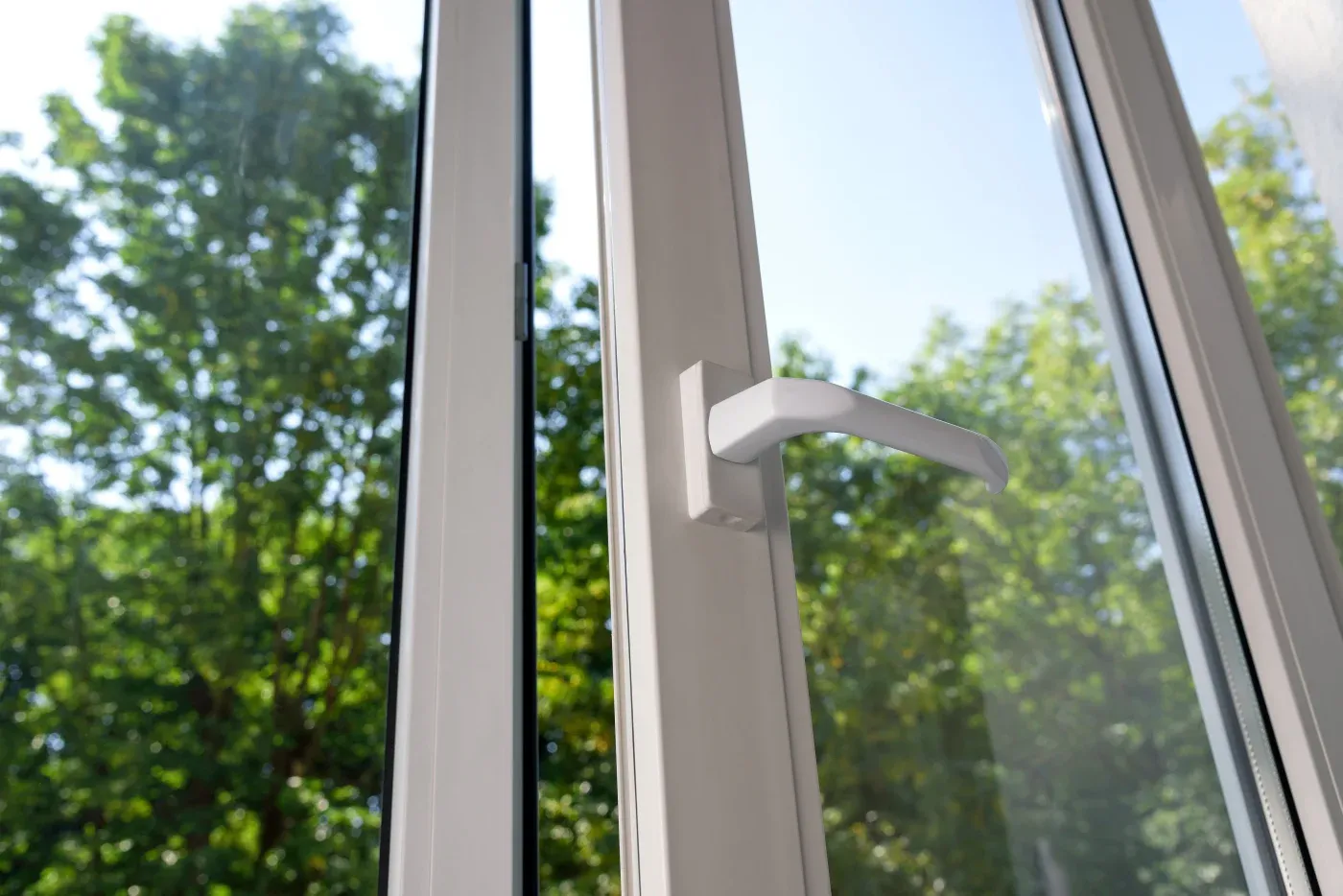 A clean vinyl replacement window is being opened to let fresh air in.